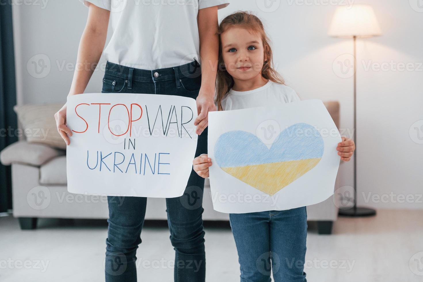 Mother with her little daughter standing with banners with text stop war in Ukrane photo