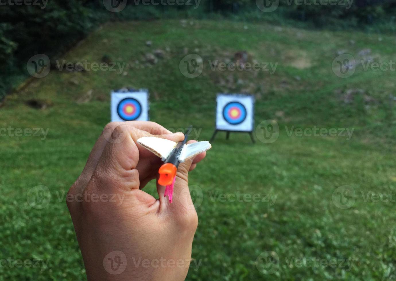 Hand holding an arrow with two targets in the background photo