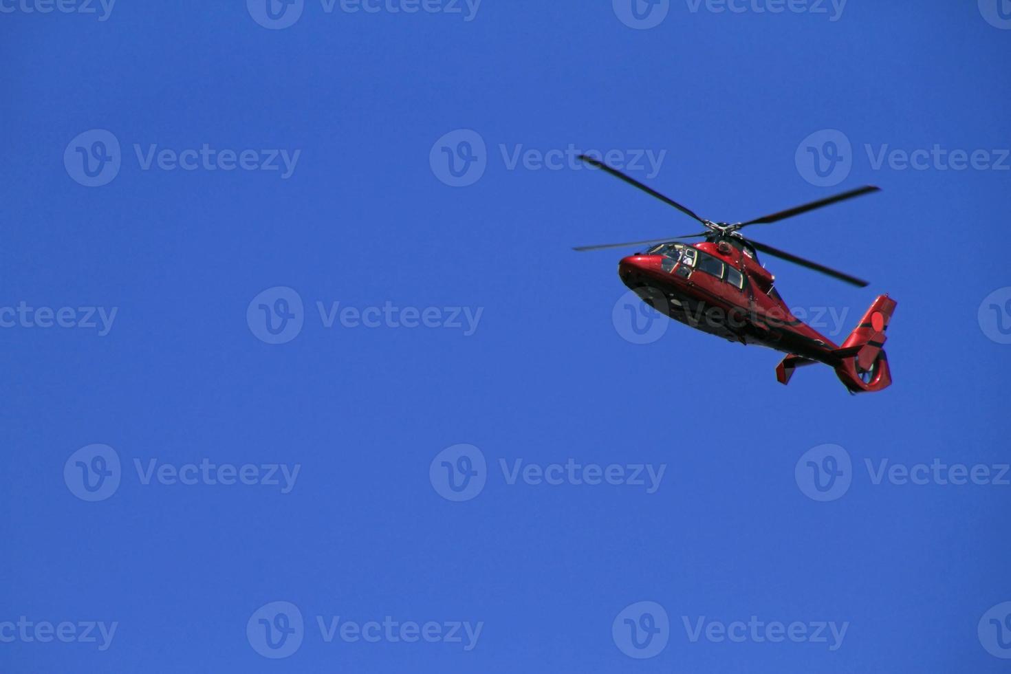 Red helicopter in the blue sky photo