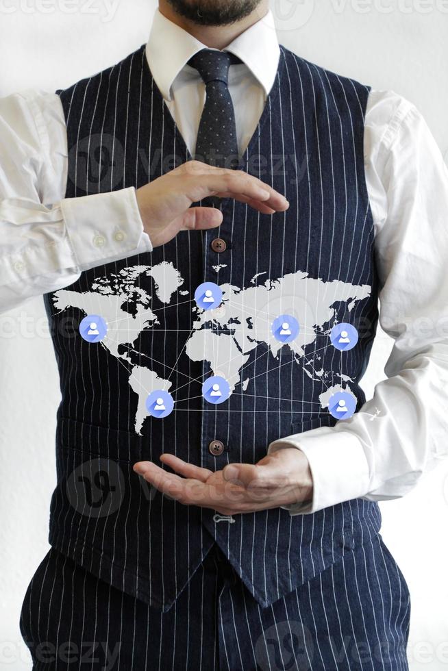 Global network - business man in suit holding a world map with business connections photo