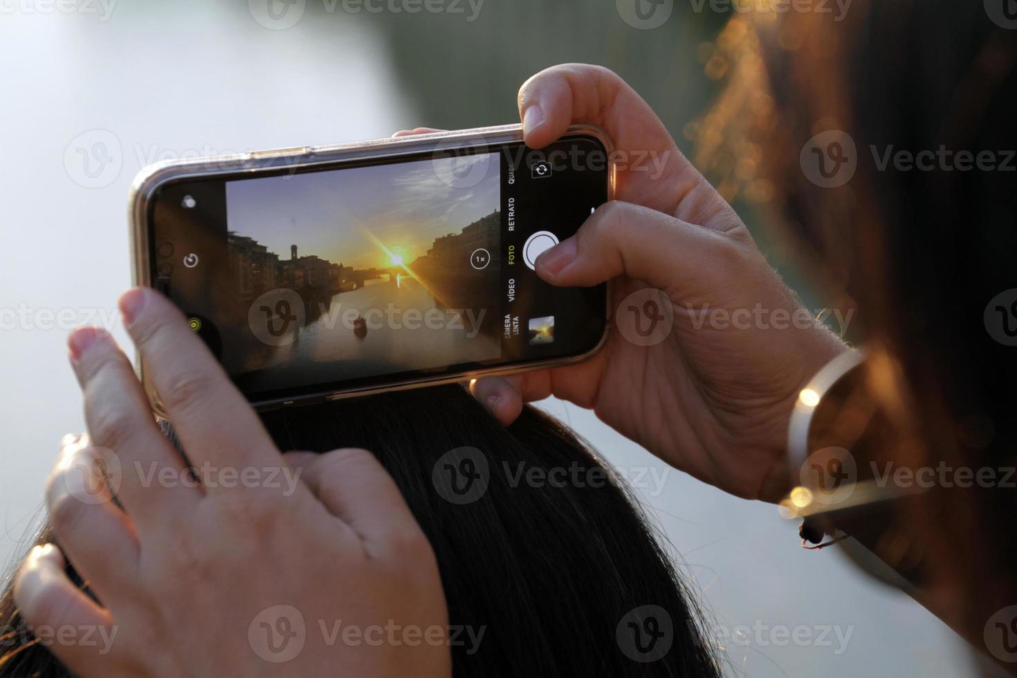 Woman taking a smartphone photo in Florence, Italy, during sunset