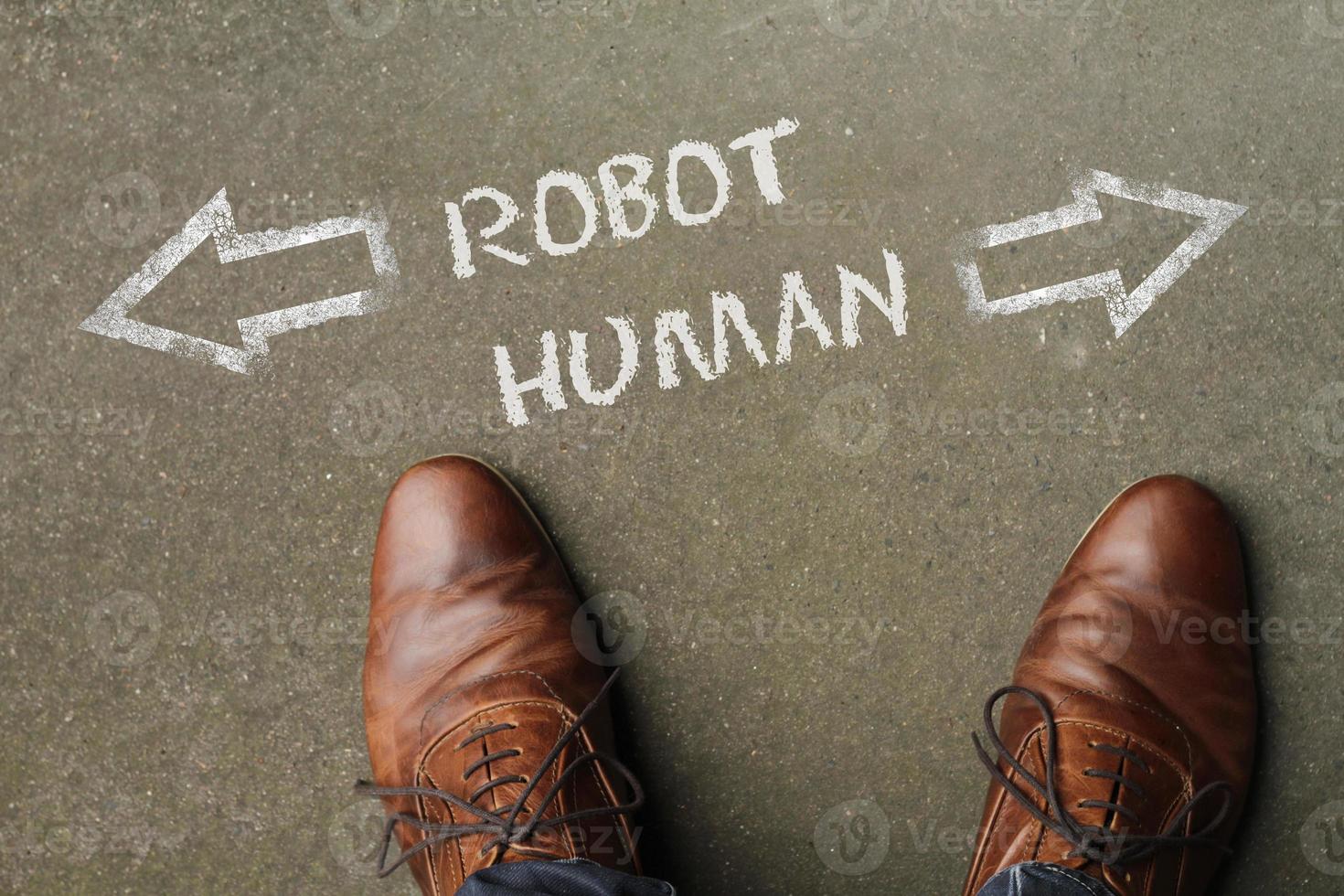 Man looking down at the words Robot and Human chalked onto the floor photo