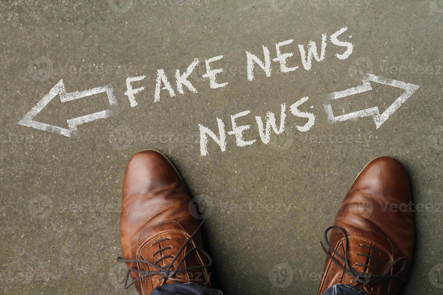 Man looking down at the words News and Fake News with arrows pointing in opposite directions photo