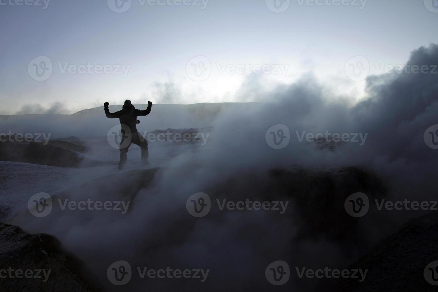 Silhouette of a man in the midst of volcanic smoke on a volcano in Salar de Uyuni, Bolivia, during sunrise photo