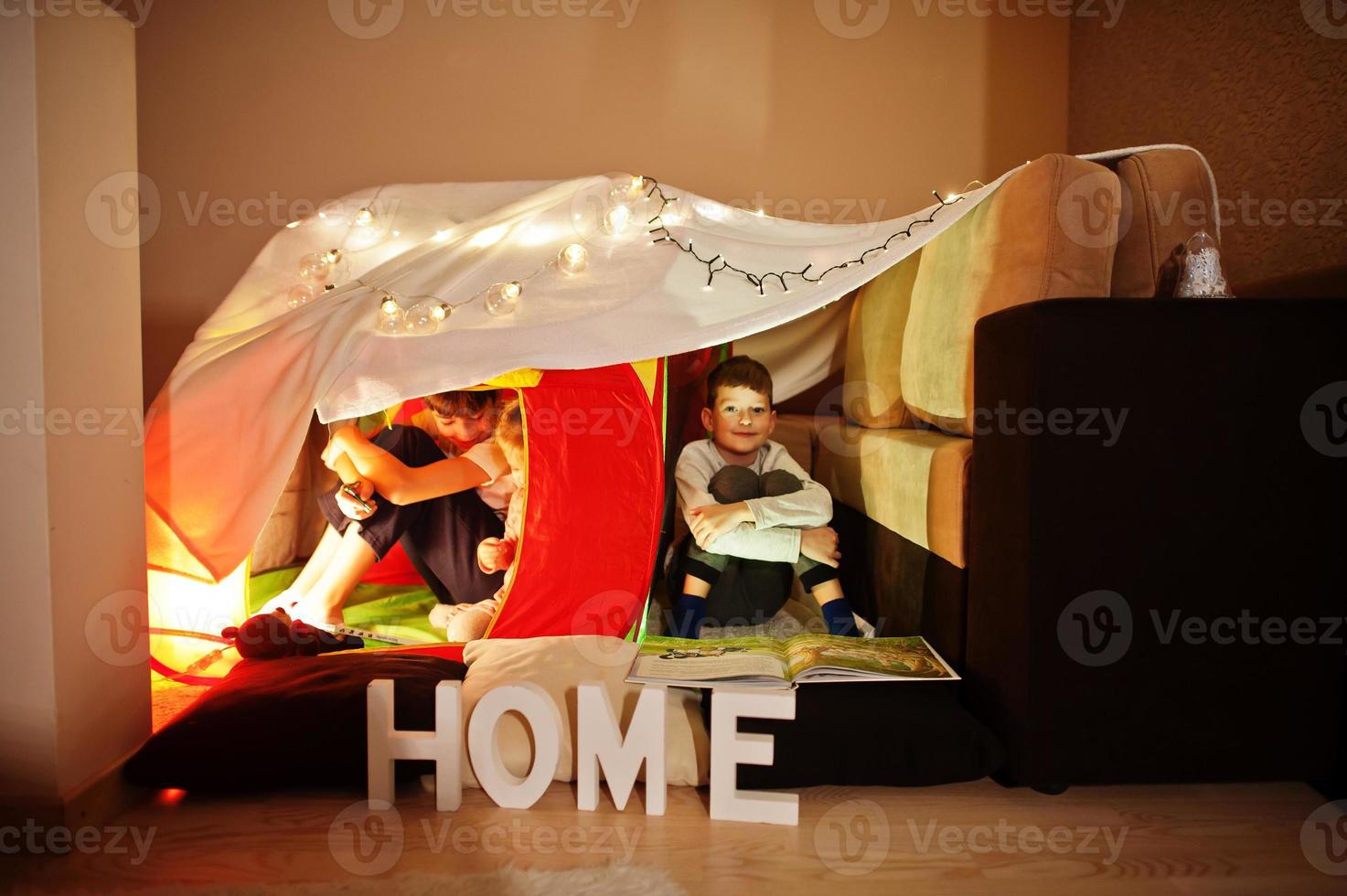 Playing kids in tent at night home. Hygge mood. photo