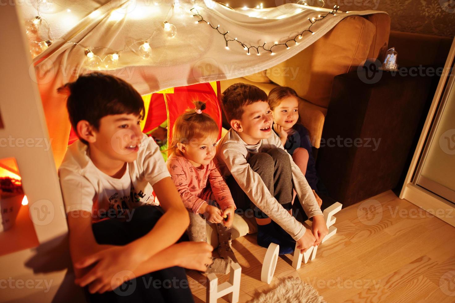 Kids in tent waching tv at night home. Hygge mood. photo