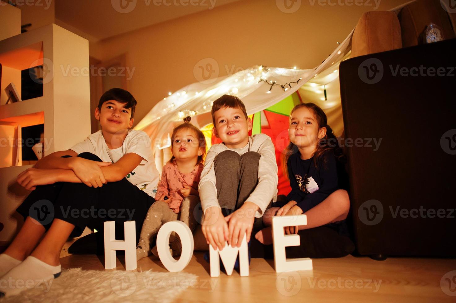 Kids in tent waching tv at night home. Hygge mood. photo