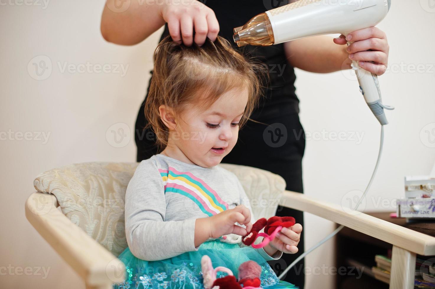 mamá con hija haciendo juntos la rutina diaria. la madre está cepillando y secando el cabello del niño después de la ducha. foto