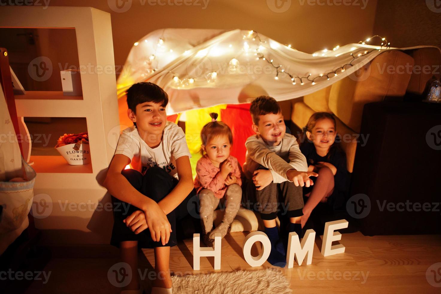 Kids in tent waching tv at night home. Hygge mood. photo