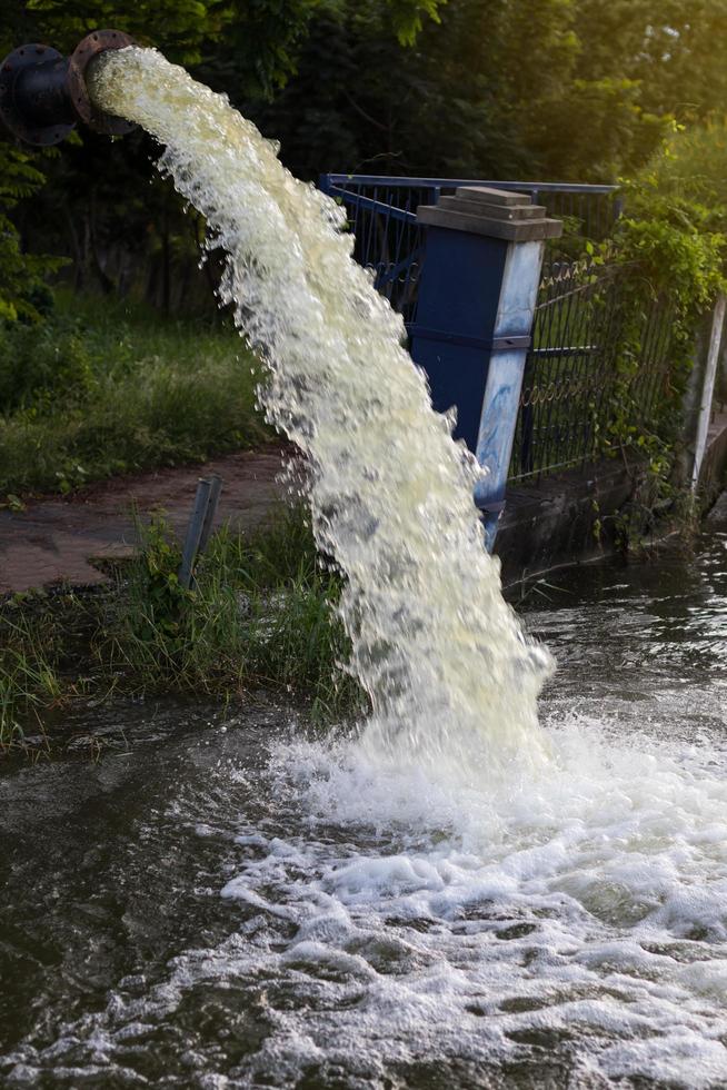 el agua fluye desde la tubería hacia el canal. foto