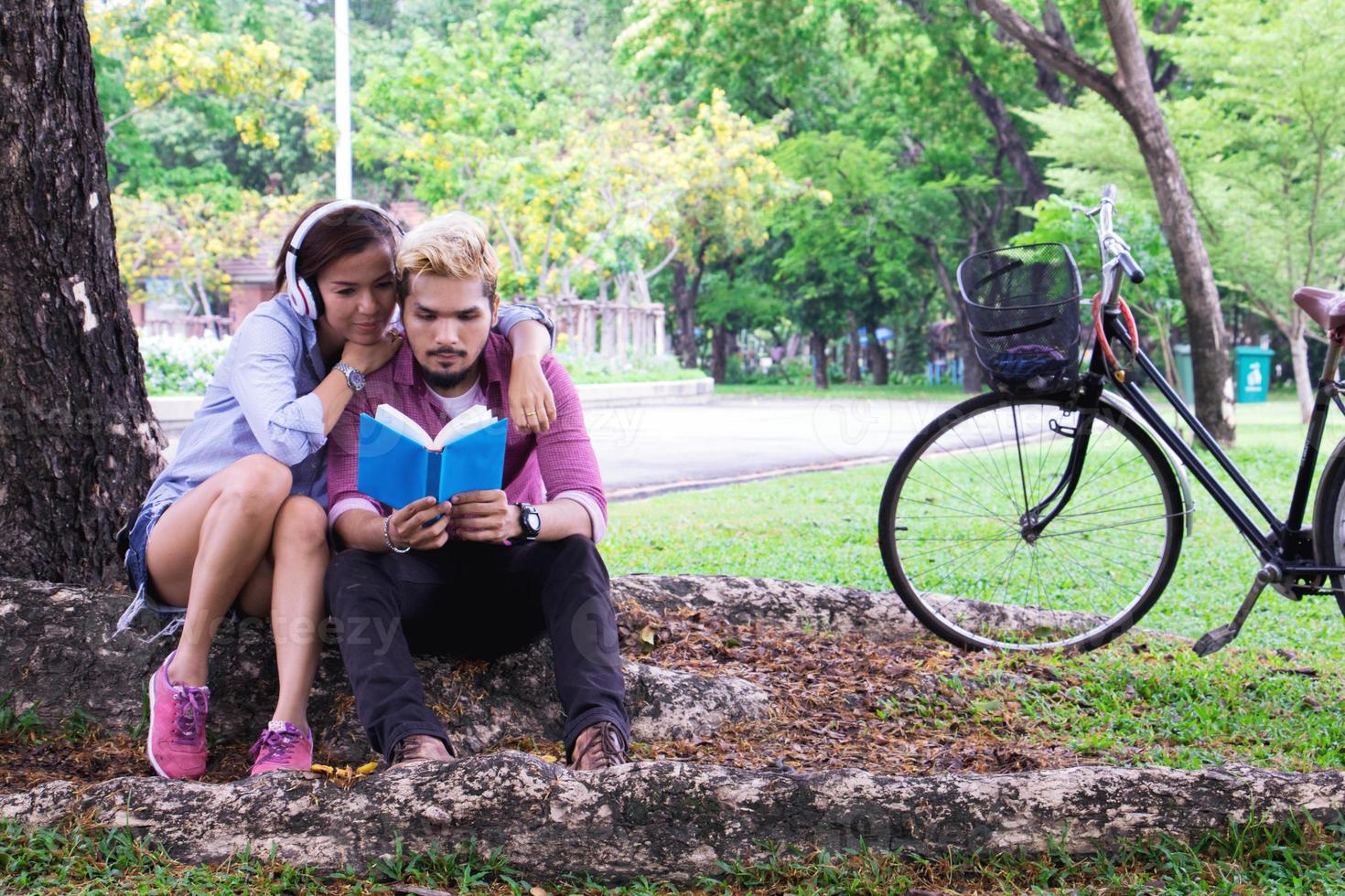 un hombre lee un libro y una mujer también lee un libro. están enamorados y se relajan en el parque público de tailandia. son el día de la luna de miel. foto