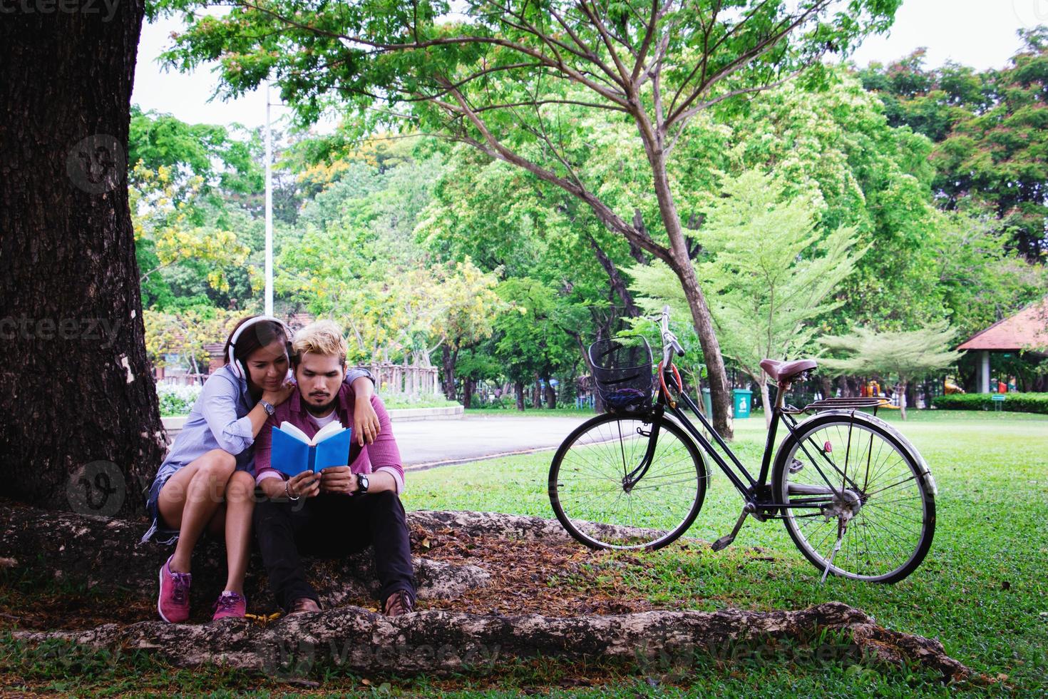 A man read a book and woman read a book too.They are in love and relax time  in public park Thailand.they are honeymoon  day. photo
