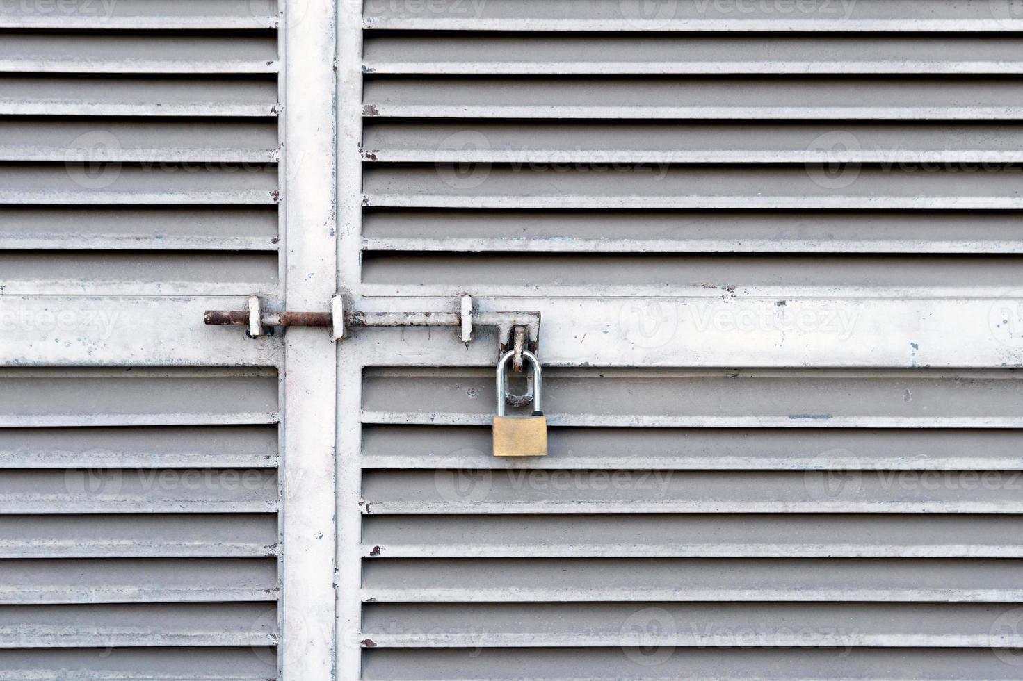 Small padlock hanging on closed metal doors photo