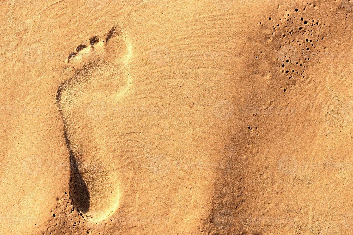 Footprint of a bare human foot in the sand photo