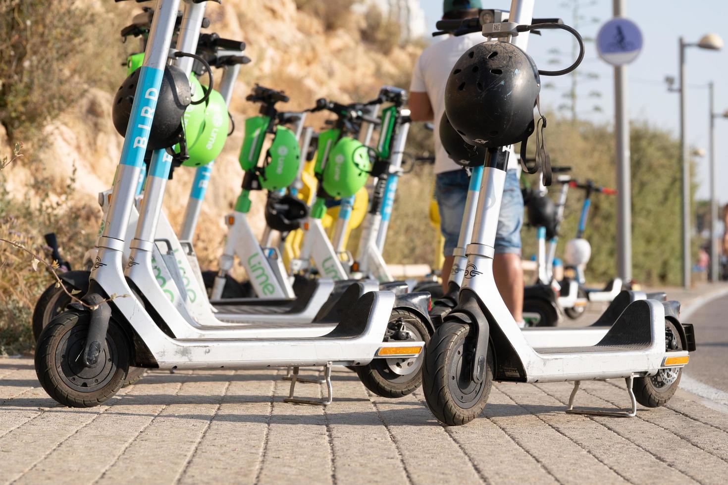 Tel Aviv Yafo, Israel-May 22, 2022. Rental electric scooters standing on the road near a beach photo