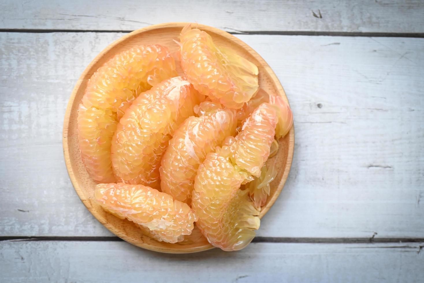 Pomelo fruit on wooden plate, fresh pomelo peeled frome pomelo tree , pummelo , grapefruit in summer tropical fruit in thailand - top view photo