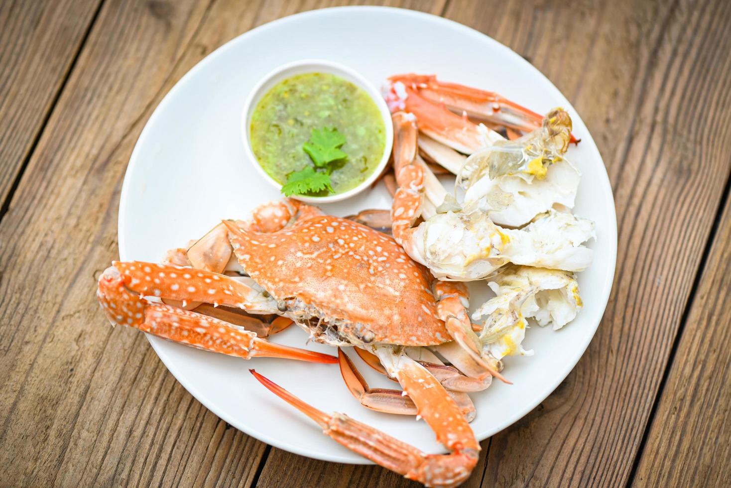 seafood plate fresh crab cooking on white plate background , blue swimming crab meat claw served on a food table - cooking steamed crab with seafood sauce top view photo