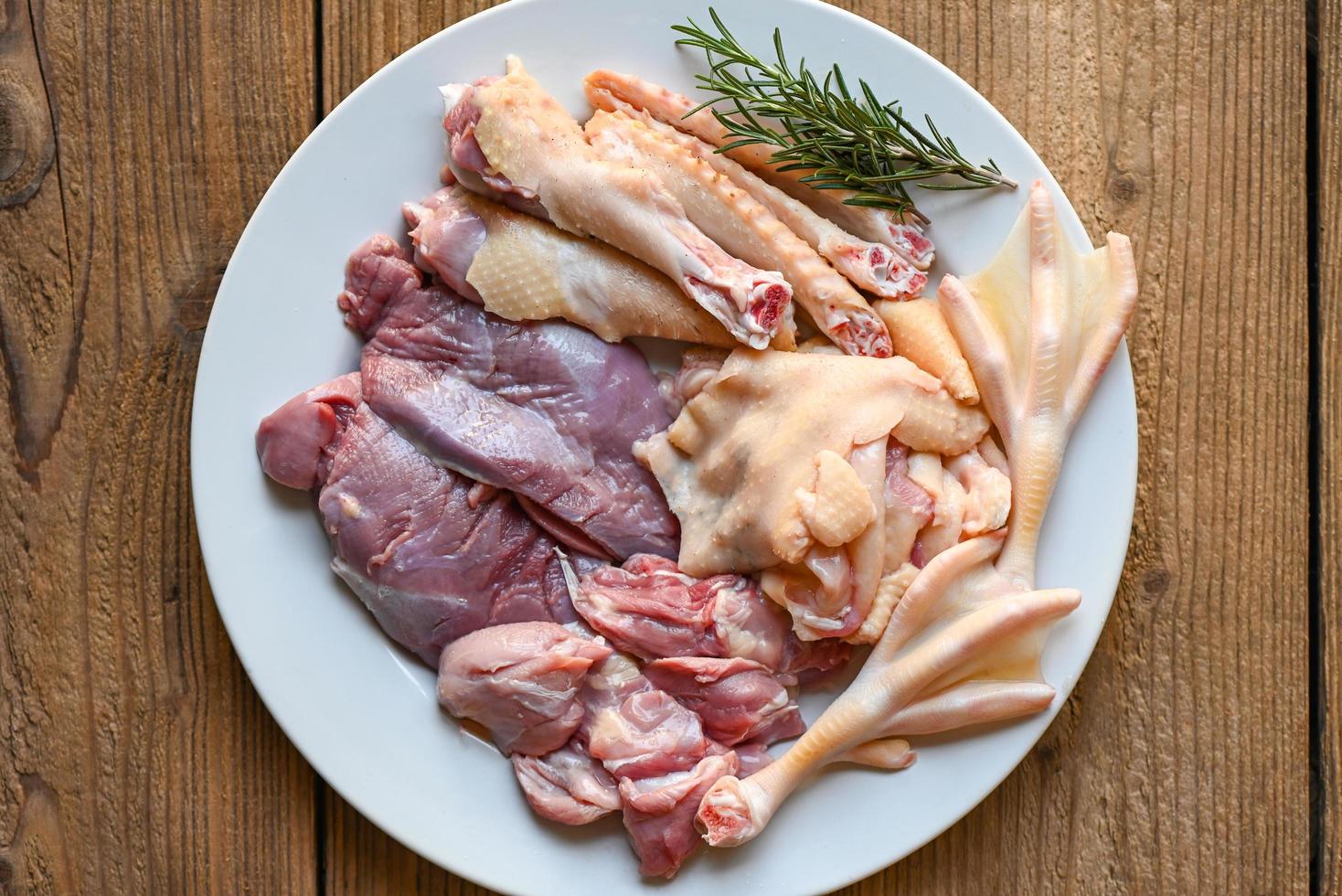 patas de pierna de pechuga de pato cruda ala de pato con especias hierbas romero para cocinar en plato blanco, carne de pato fresca para comida, piezas de carne de ave foto