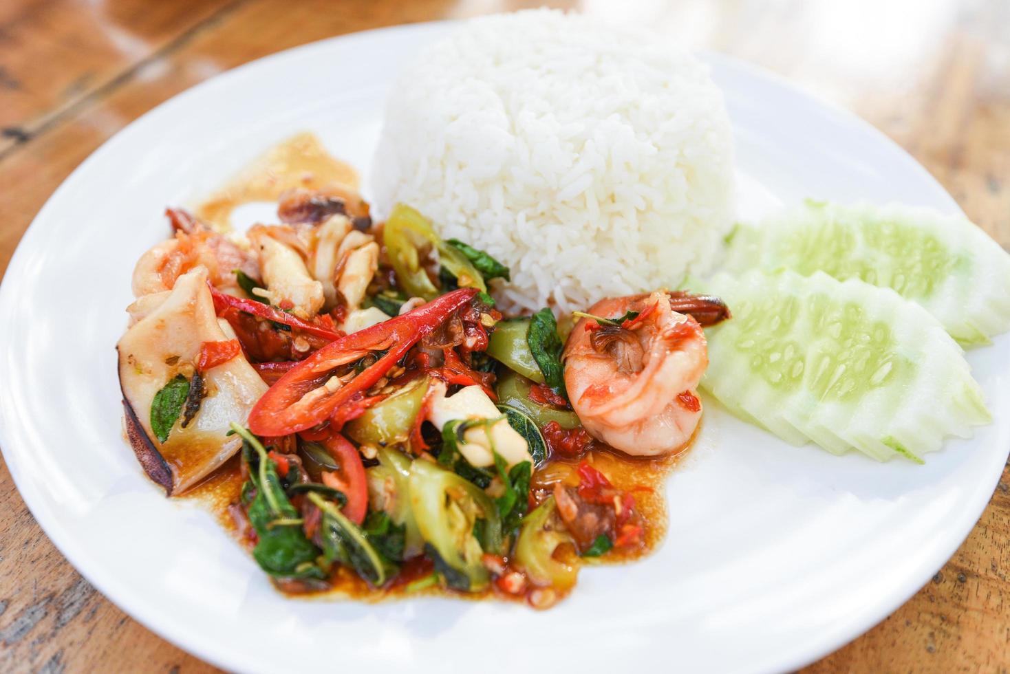 Stir fried seafood squid shrimp prawn with holy basil and rice - Thai food spicy fried recipe with cucumber and chili photo