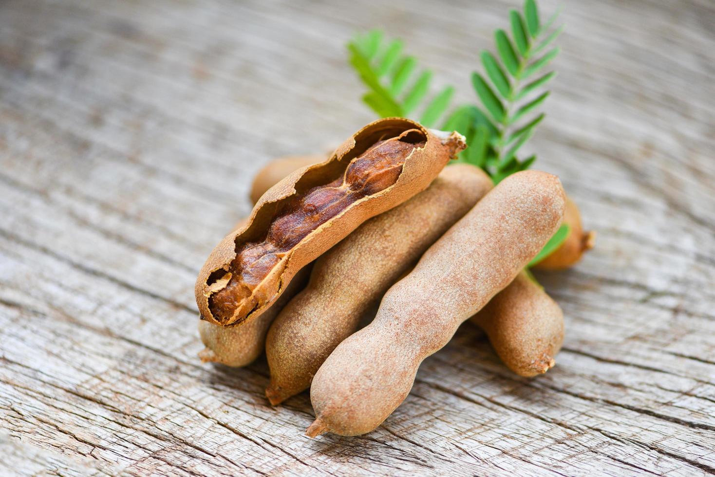 tamarindo y hojas de frutas tropicales - tamarindo dulce sobre fondo de madera foto