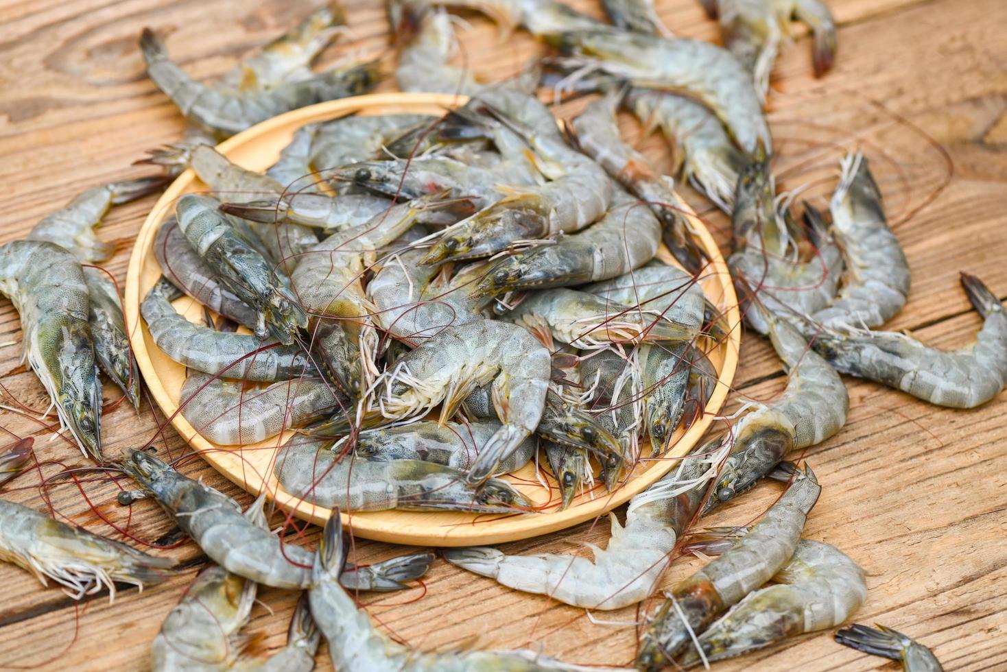 camarones crudos en plato de madera y fondo de camarones para cocinar, camarones o langostinos frescos de cerca, estantes de mariscos foto