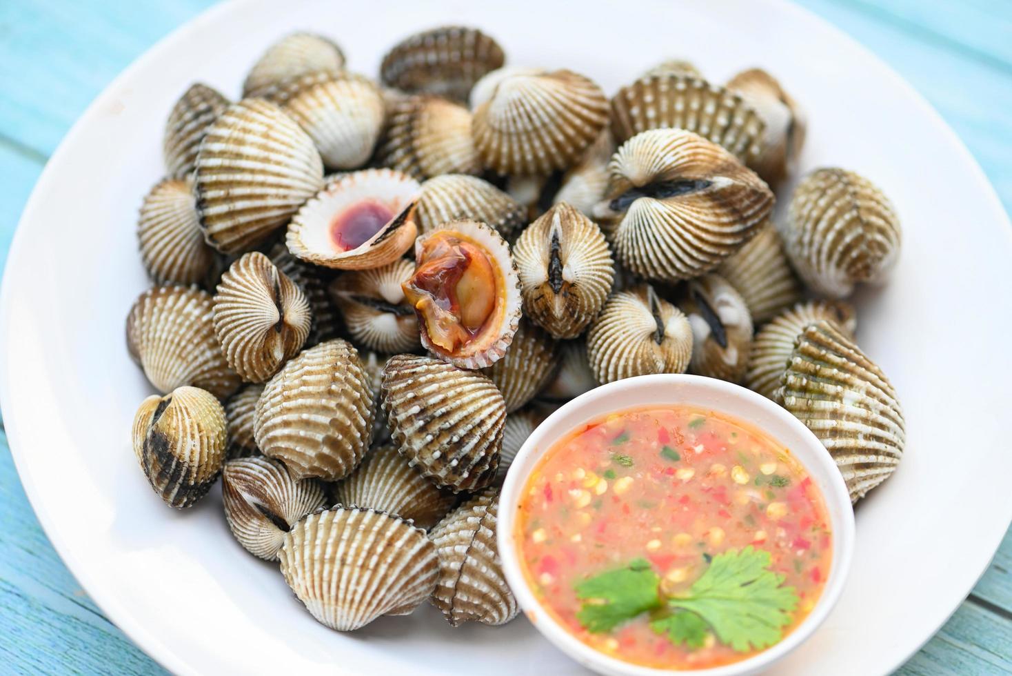 Cockles on white plate with seafood sauce on table background , Fresh raw shellfish blood cockle ocean gourmet seafood in the restaurant photo