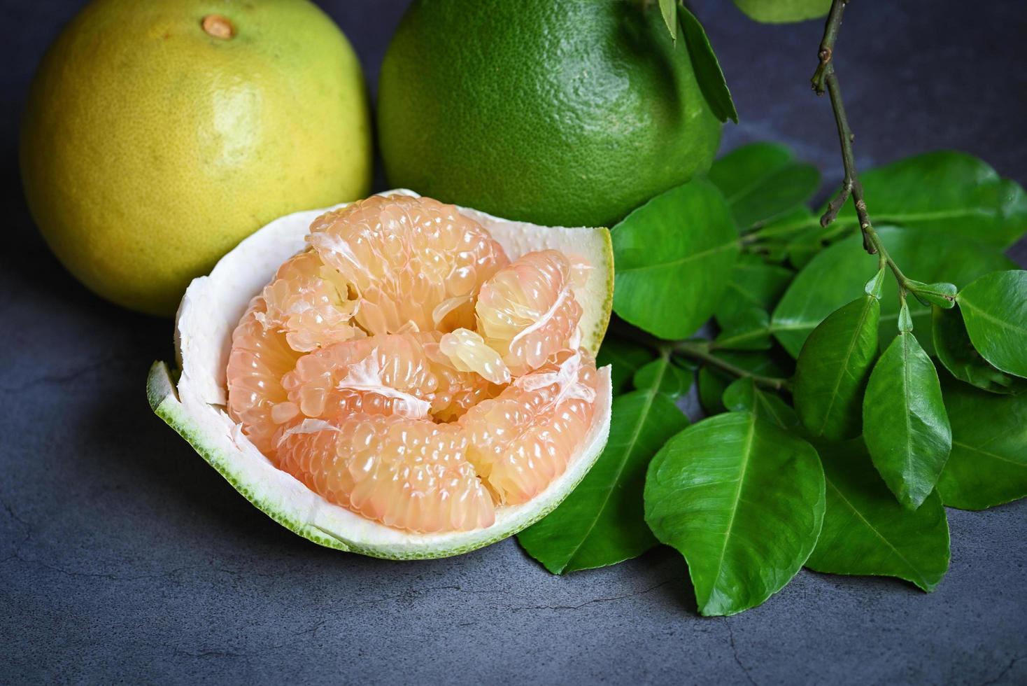 pomelo fruit and dark background, fresh green pomelo peeled on plate and green leaf frome pomelo tree , pummelo , grapefruit in summer tropical fruit  in thailand photo