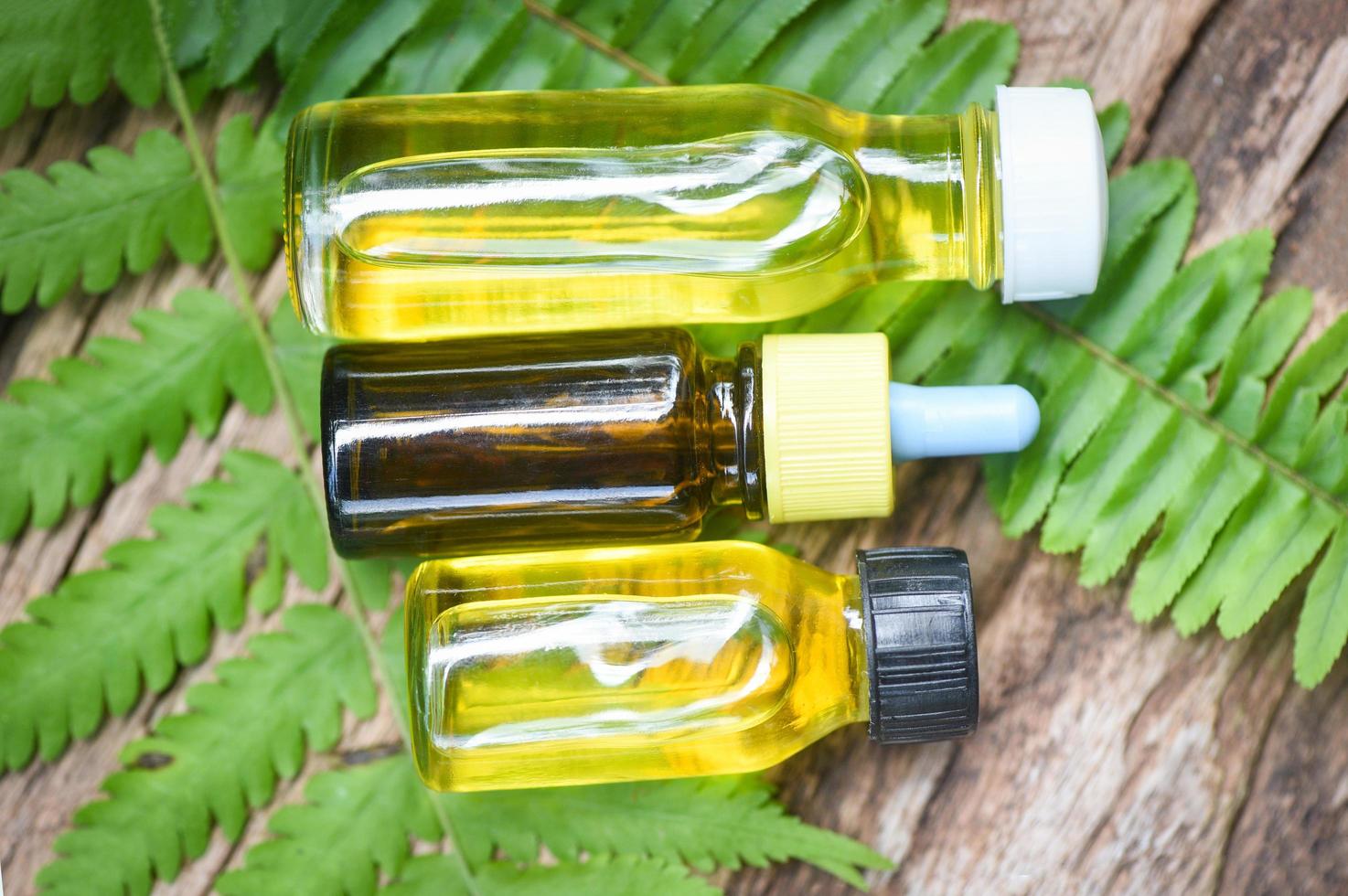 Herbal oil bottles aroma with fern leaves herbal formulations including wildflowers and herbs on wood - Essential oils natural on wooden and green leaf organic photo