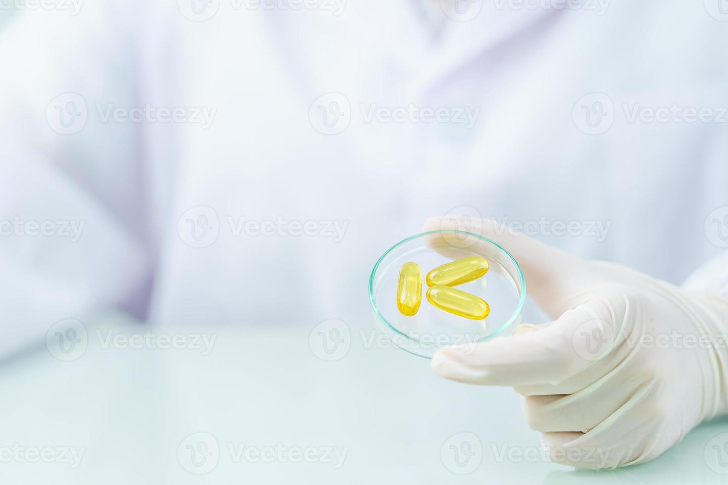 Close up Scientist holding Omega 3 capsule in labcoat photo