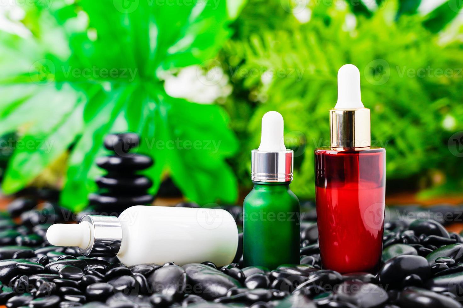 Cosmetic glass bottle for essential oils on black stone photo