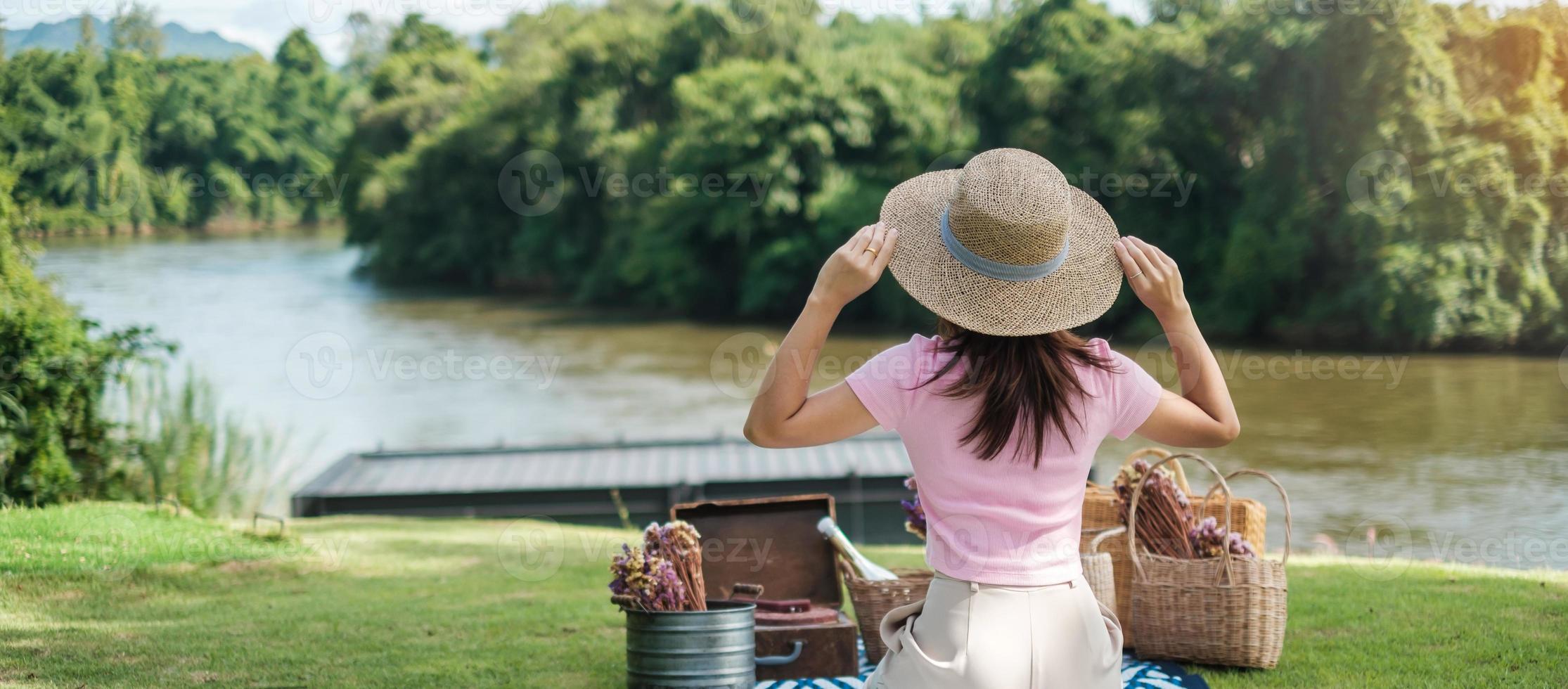 mujer feliz con sombrero en tiempo de picnic en el parque cerca del concepto de río, verano, primavera y vacaciones foto