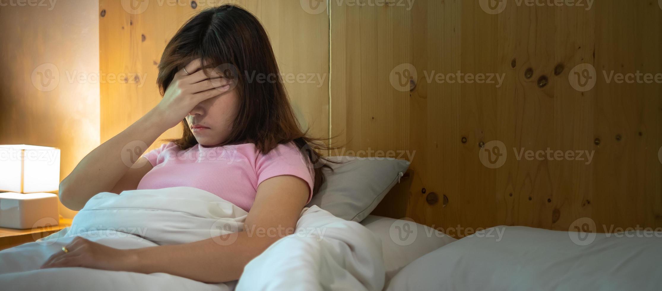 mujer que tiene dolores de cabeza por migraña mientras está acostado en la cama en casa. conceptos de insomnio, insomnio, cansancio, sufrimiento y estrés foto