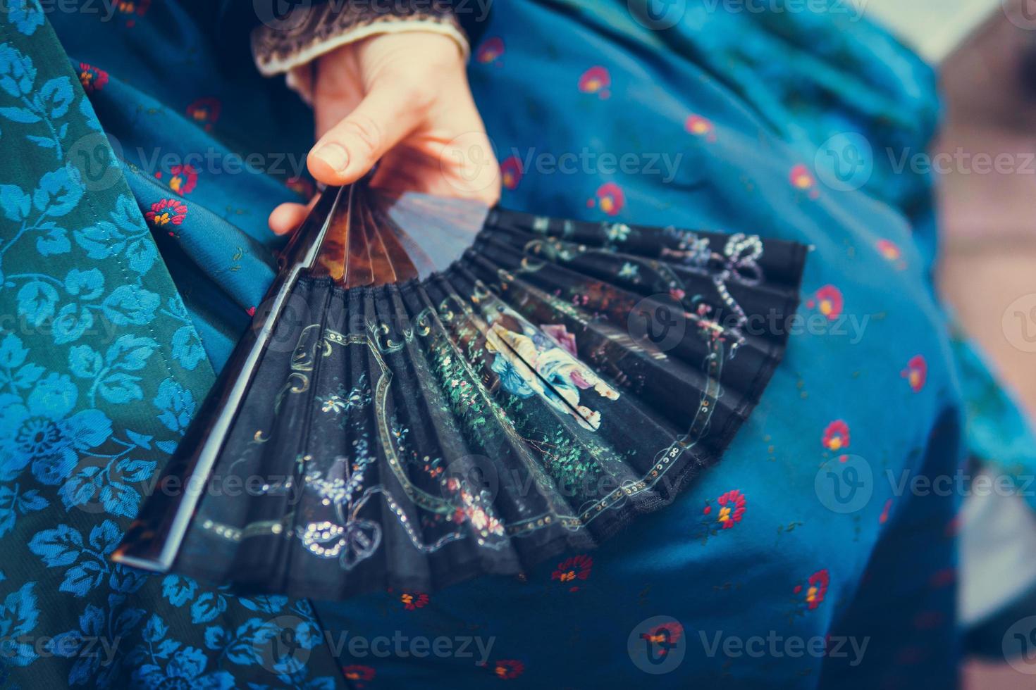 Luxurious medieval hand fan in the female hand, close-up photo