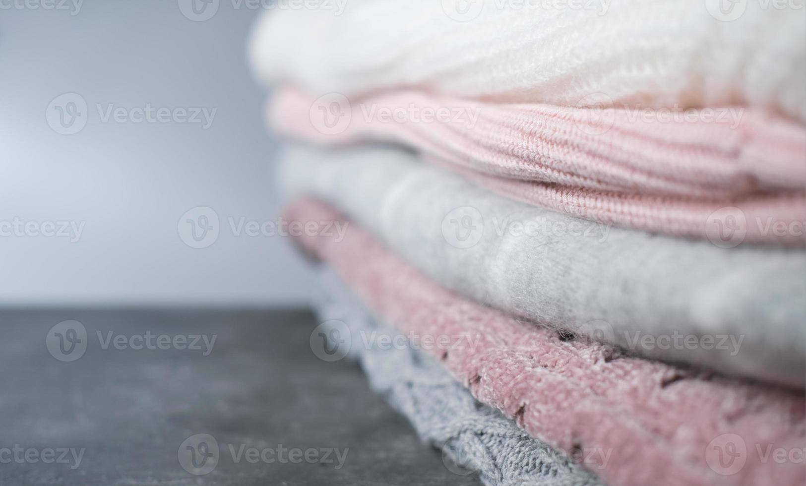 a pile of knitted sweaters in grey and pink colors. photo