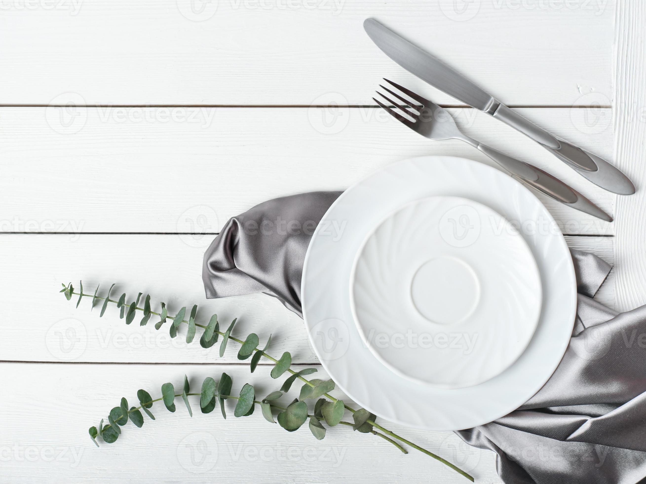 top view of simple white table setting with silk napkin and green