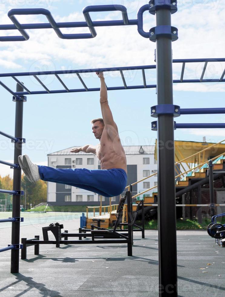 toned man of middle age hanging on a monkey bars photo