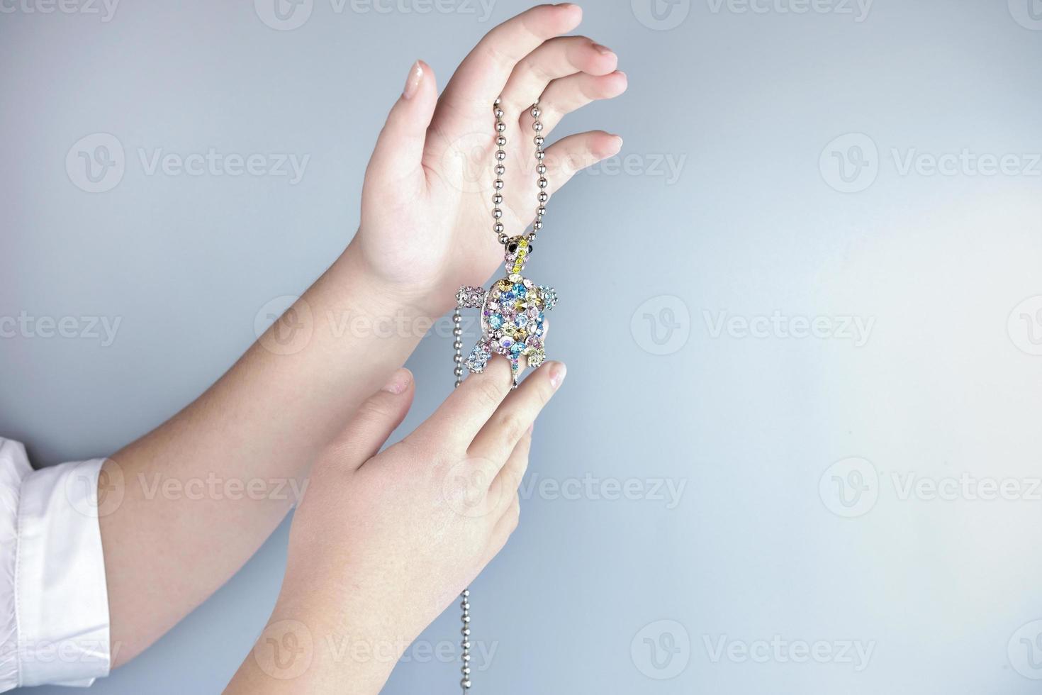 teenager's hand holding a gem turtle pendant photo