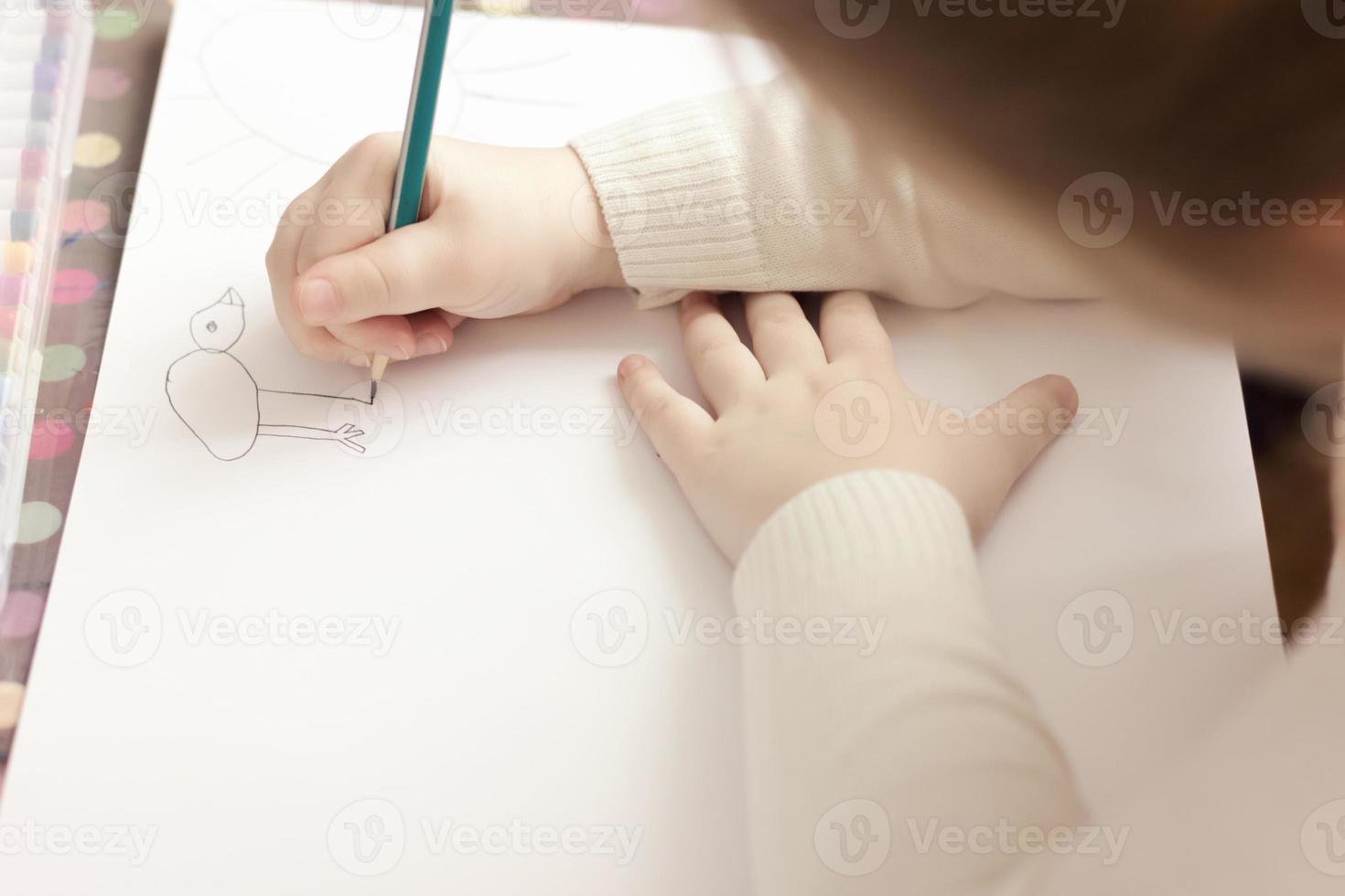 cropped view of little girl drawing with a pencil. photo