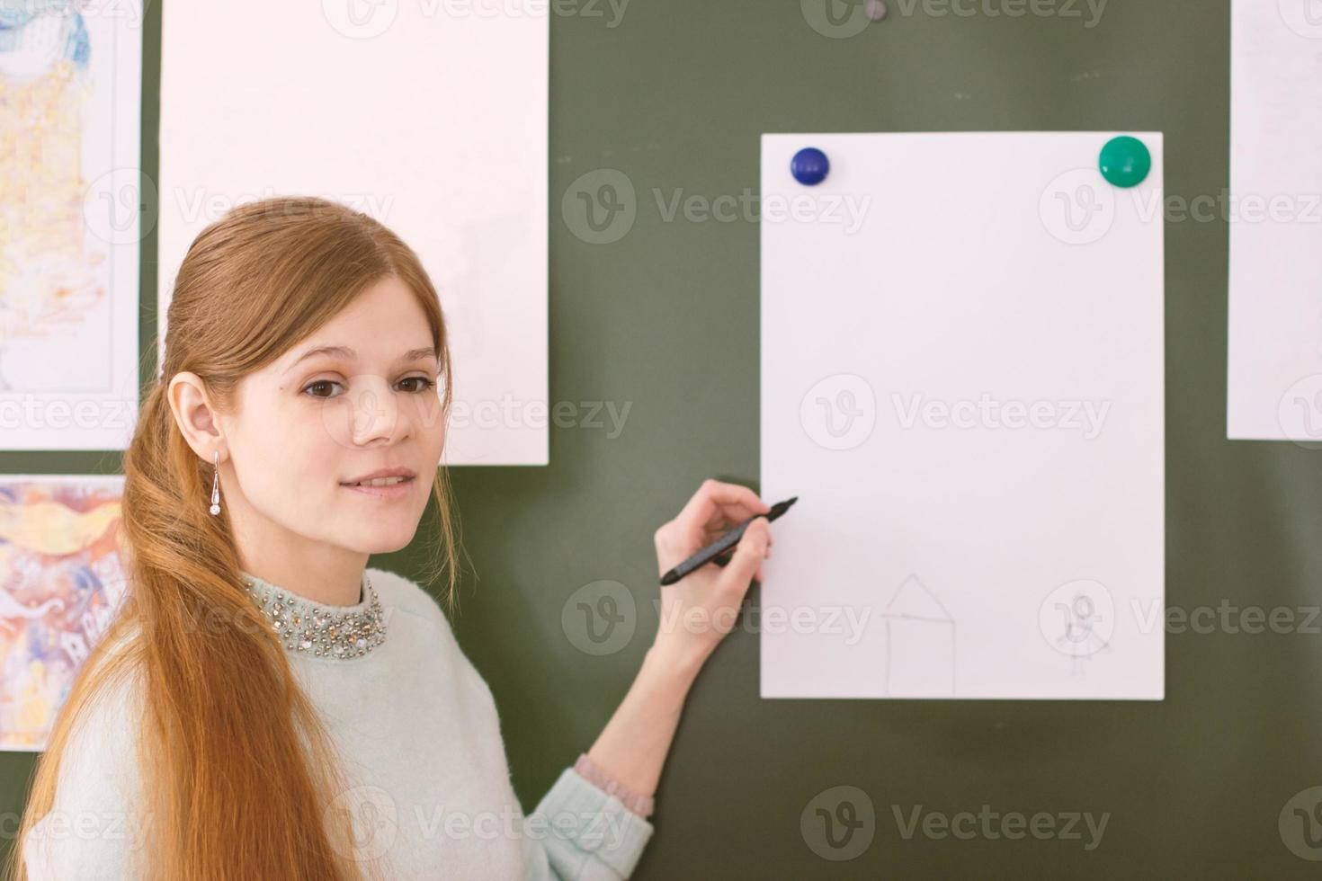 young beautiful art teacher explains children how to draw a picture. photo