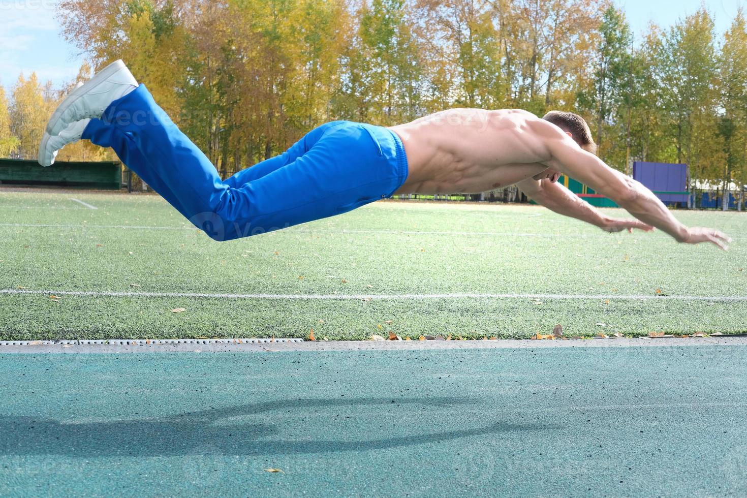 middle aged man doing jumping push-ups on a stadium. photo