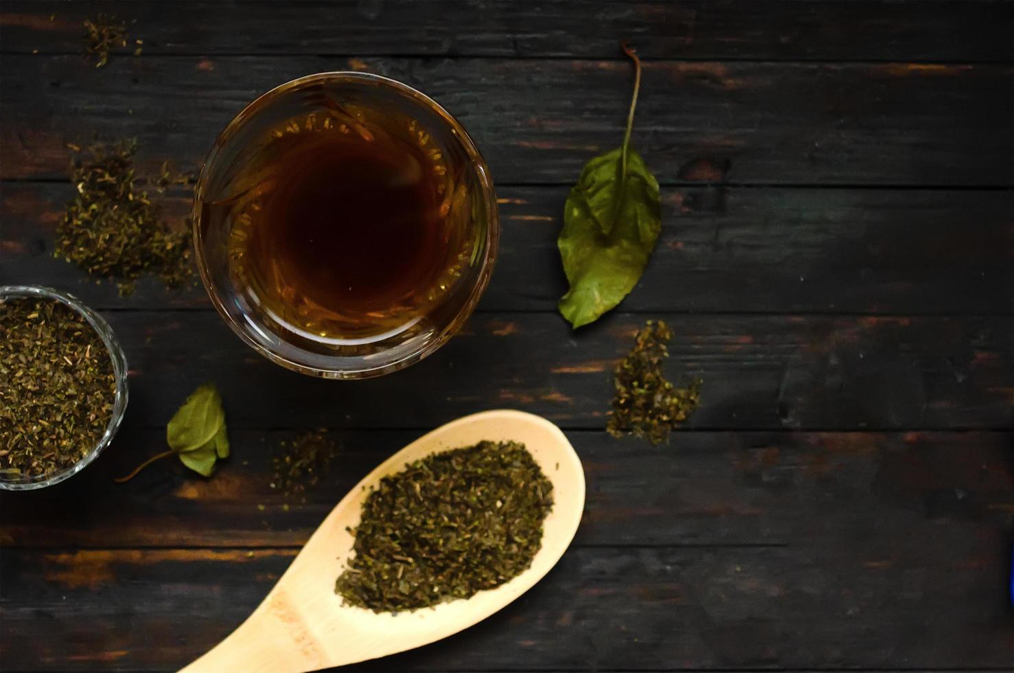 Green tea composition.Top view, a glass of green tea and a spoon with a little green tea on wooden table, copyspace. photo