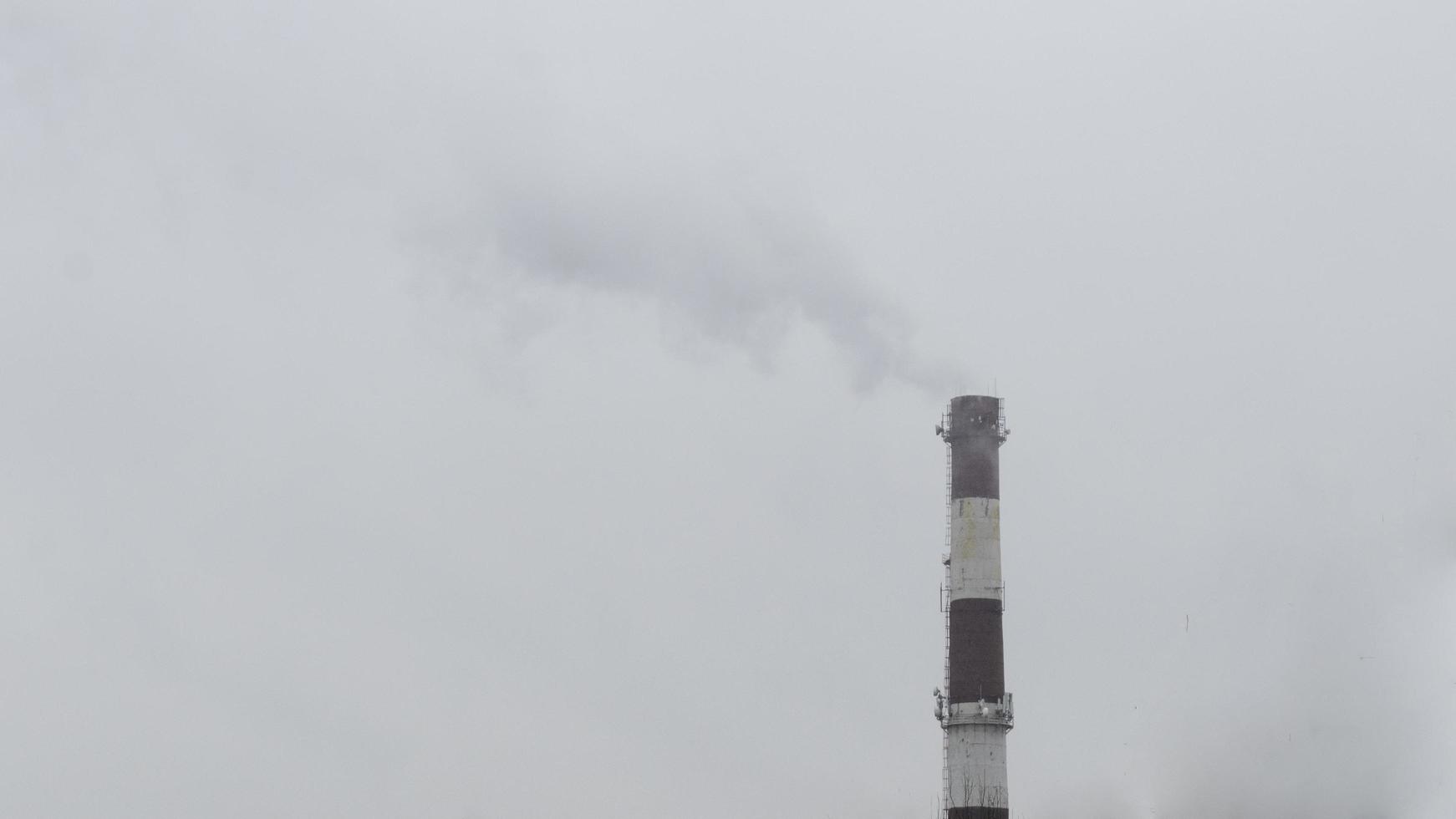 Atmospheric pollution.Smoke from the factory pipe in cloudy day. photo