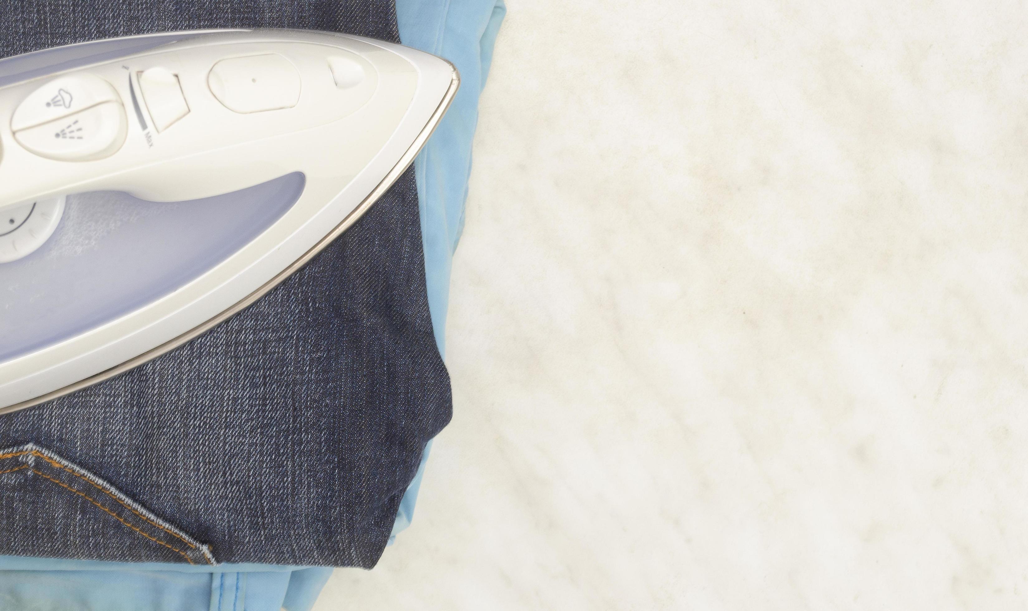 Steam iron, classic jeans and summer jeans on a light background, copy