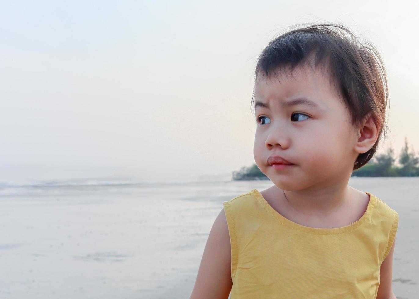 chica asiática de pie con expresión preocupada en la playa. foto