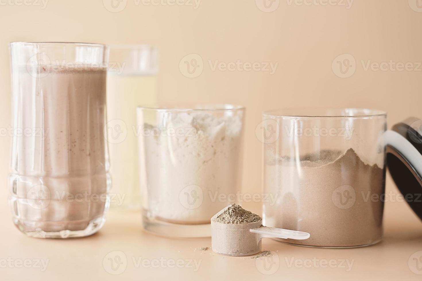 whey protein drink in a glass and jars with protein powder on beige background. chocolate and vanilla flavored supplement for healty lifestyle photo