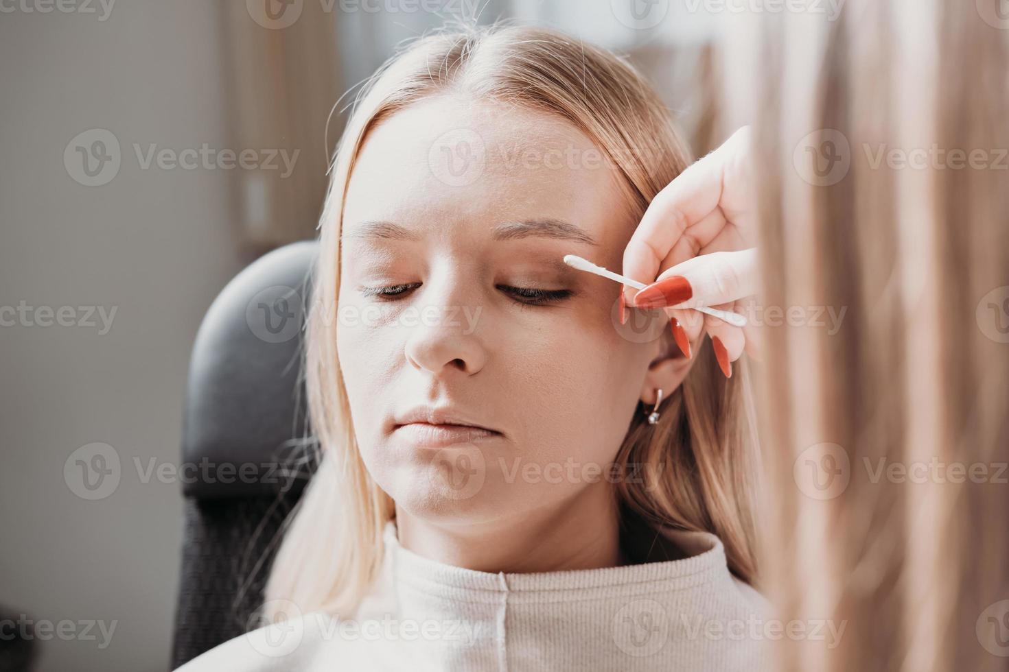 make up artist making corrections in model's make-up. woman model with eyes closed in a beauty salon, applying eye shadows. photo