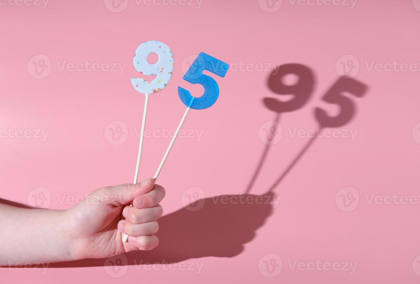 girl's hand holding a number 95 shaped lolipop. photo