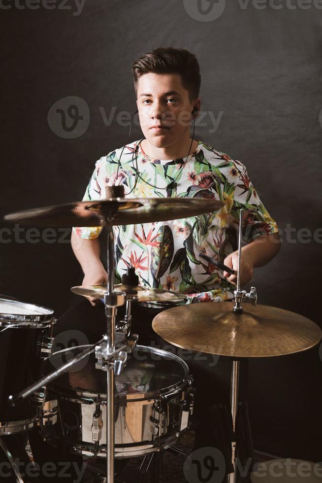 baterista de niño adolescente jugando en el ensayo en un estudio. músico de rock adolescente masculino interpretando una canción. concepto de hobby y ocio. tamaño vertical foto