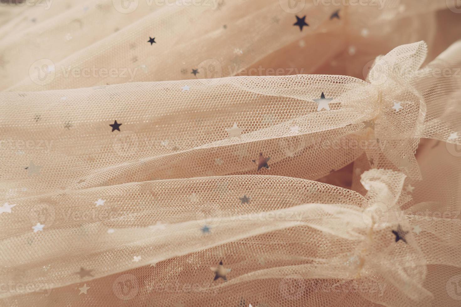 festive tulle fabric with stars. texture of beige mesh fabric photo