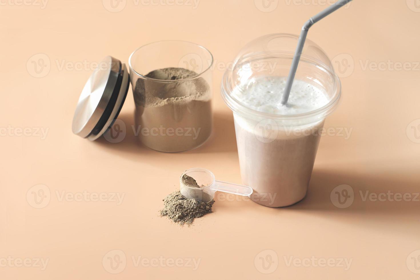 whey drink in plastic cup and a jar with chocolate protein powder and a scoop on a table. protein supplement for healthy muscle building and athletic nutrition photo